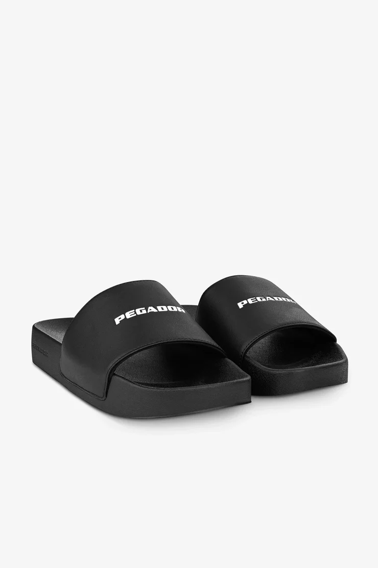 pegador-logo-slide-black-white παντόφλες σε μαύρο χρώμα και με λευκή επιγραφή της εταιρείας στο πάνω μέρος, pegador logo slide black white