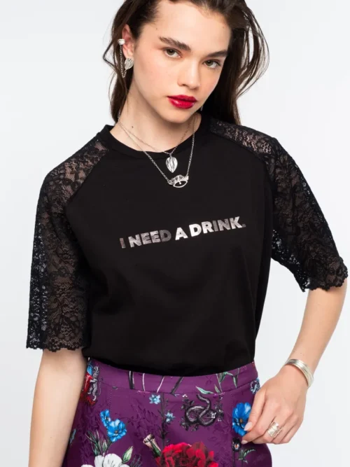 Το Icon T-Shirt συνδυάζει το διαχρονικό μαύρο βαμβακερό ύφασμα με ιδιαίτερες λεπτομέρειες από δαντέλα και ένα ξεχωριστό foil print που αναγράφει “I need a drink”.