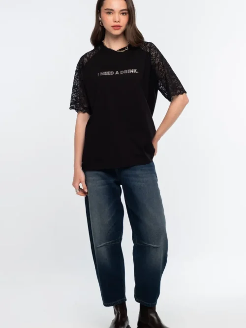 Το Icon T-Shirt συνδυάζει το διαχρονικό μαύρο βαμβακερό ύφασμα με ιδιαίτερες λεπτομέρειες από δαντέλα και ένα ξεχωριστό foil print που αναγράφει “I need a drink”.