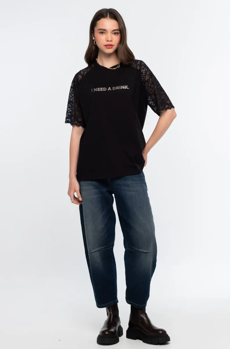 Το Icon T-Shirt συνδυάζει το διαχρονικό μαύρο βαμβακερό ύφασμα με ιδιαίτερες λεπτομέρειες από δαντέλα και ένα ξεχωριστό foil print που αναγράφει “I need a drink”.