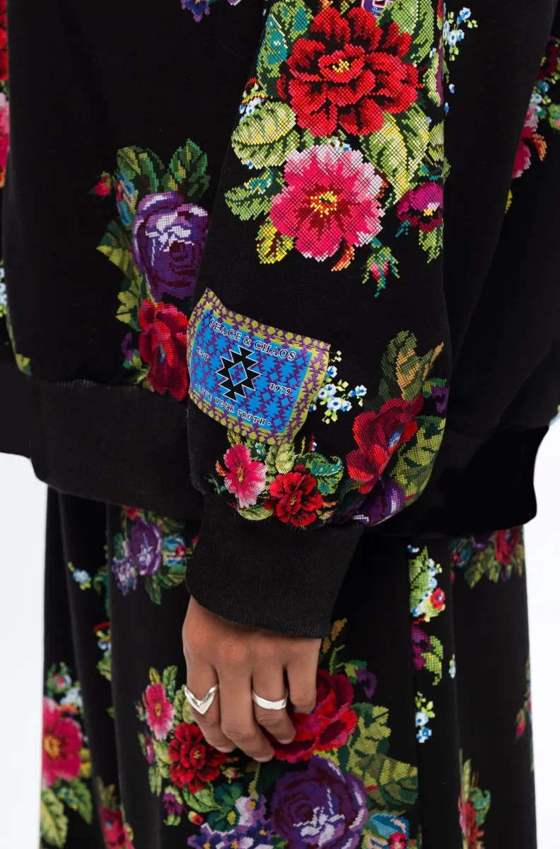 Το Bouquet Sweater συνδυάζει τη relaxed αισθητική ενός sweatshirt με θηλυκές, ιδιαίτερες λεπτομέρειες. Οι διακριτικές bishop sleeves και το εντυπωσιακό all-over print με ψηφιακά σχεδιασμένα λουλούδια εμπνευσμένα από την τεχνική του cross stitch χαρίζουν στο κομμάτι ξεχωριστό χαρακτήρα.