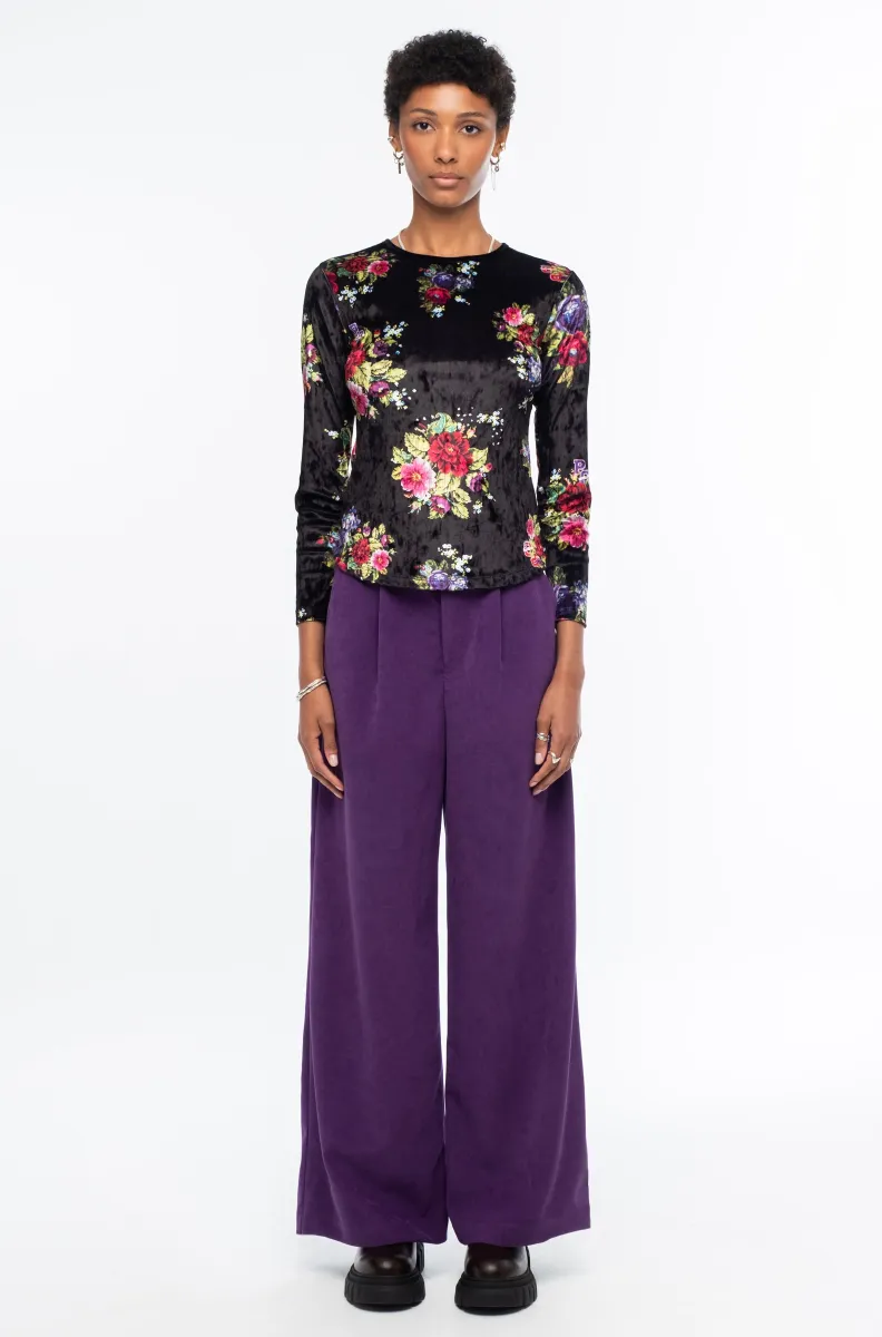 Το Bouquet Top ξεχωρίζει για το εντυπωσιακό all-over floral print με ψηφιακά λουλούδια εμπνευσμένα από την τεχνική του cross stitch, πάνω σε μαύρο ice velvet με ιδιαίτερη ανάγλυφη υφή.