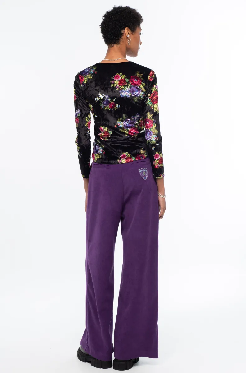 Το Bouquet Top ξεχωρίζει για το εντυπωσιακό all-over floral print με ψηφιακά λουλούδια εμπνευσμένα από την τεχνική του cross stitch, πάνω σε μαύρο ice velvet με ιδιαίτερη ανάγλυφη υφή.