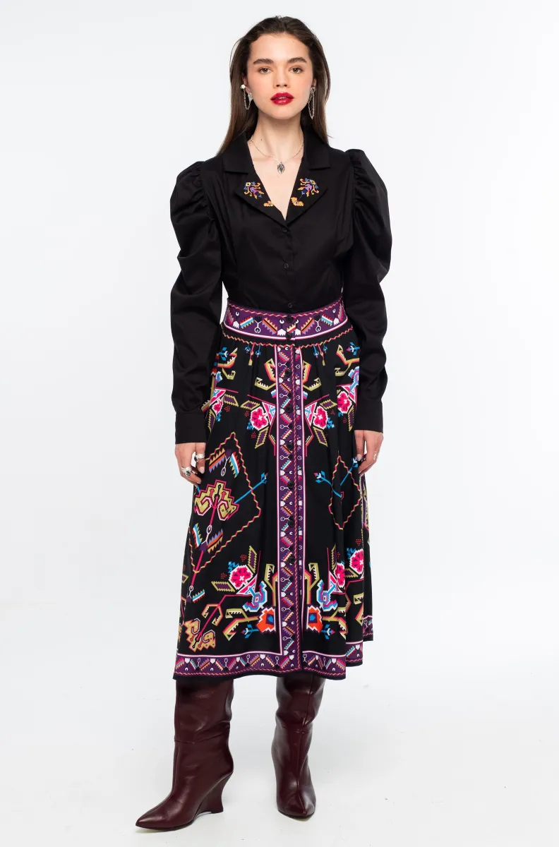Η Emblem Midi Skirt της Peace + Chaos είναι μια εντυπωσιακή midi φούστα σε A-line γραμμή, με ιδιαίτερο placement print εμπνευσμένο από ψηφιακές αναπαραστάσεις παραδοσιακών μοτίβων λαϊκής τέχνης, διακοσμητικών borders και κεντημάτων.