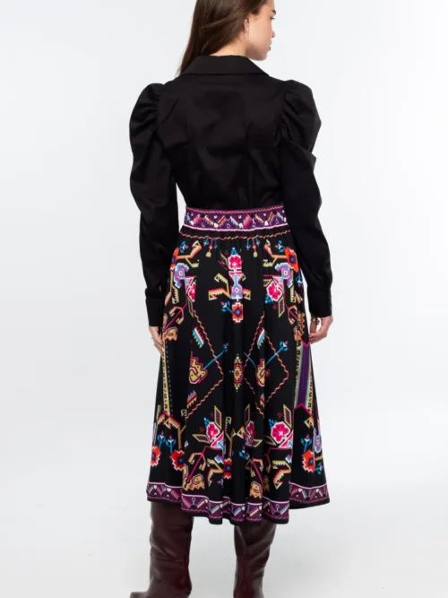 Η Emblem Midi Skirt της Peace + Chaos είναι μια εντυπωσιακή midi φούστα σε A-line γραμμή, με ιδιαίτερο placement print εμπνευσμένο από ψηφιακές αναπαραστάσεις παραδοσιακών μοτίβων λαϊκής τέχνης, διακοσμητικών borders και κεντημάτων.