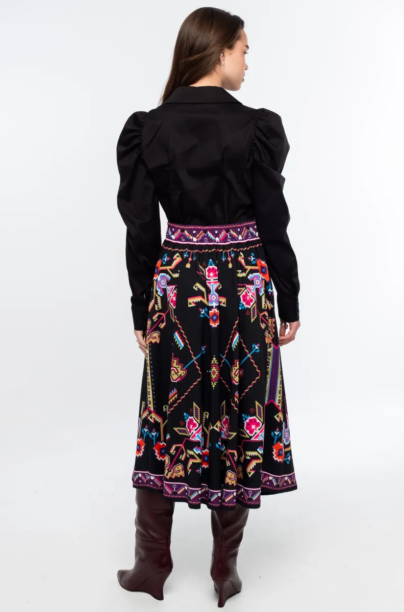 Η Emblem Midi Skirt της Peace + Chaos είναι μια εντυπωσιακή midi φούστα σε A-line γραμμή, με ιδιαίτερο placement print εμπνευσμένο από ψηφιακές αναπαραστάσεις παραδοσιακών μοτίβων λαϊκής τέχνης, διακοσμητικών borders και κεντημάτων.
