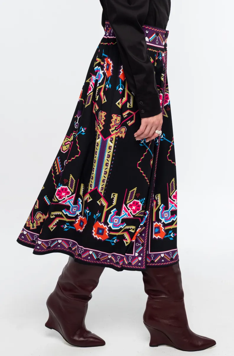 Η Emblem Midi Skirt της Peace + Chaos είναι μια εντυπωσιακή midi φούστα σε A-line γραμμή, με ιδιαίτερο placement print εμπνευσμένο από ψηφιακές αναπαραστάσεις παραδοσιακών μοτίβων λαϊκής τέχνης, διακοσμητικών borders και κεντημάτων.