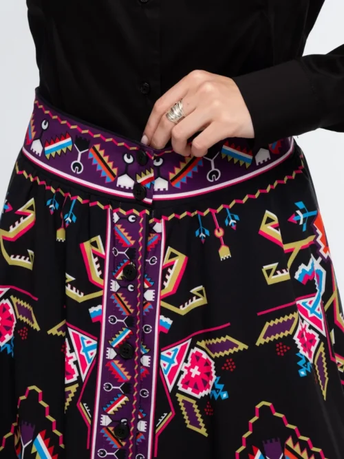 Η Emblem Midi Skirt της Peace + Chaos είναι μια εντυπωσιακή midi φούστα σε A-line γραμμή, με ιδιαίτερο placement print εμπνευσμένο από ψηφιακές αναπαραστάσεις παραδοσιακών μοτίβων λαϊκής τέχνης, διακοσμητικών borders και κεντημάτων.