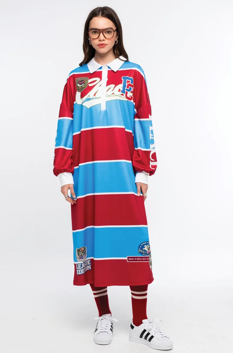 Το Semester Long Dress της Peace + Chaos συνδυάζει τη sporty αισθητική ενός rugby shirt με μια άνετη και μοντέρνα μακριά γραμμή. Κατασκευασμένο από ελαφρύ ύφασμα τύπου φούτερ, διαθέτει ιδιαίτερο placement print με διαδοχικές κόκκινες και μπλε ρίγες, varsity στοιχεία και αθλητικές αναφορές, δημιουργώντας ένα ξεχωριστό statement look.