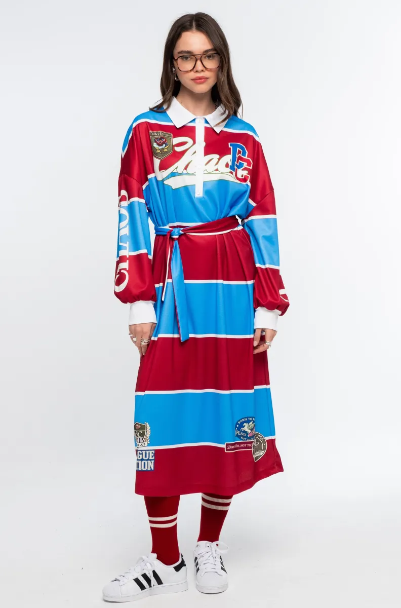 Το Semester Long Dress της Peace + Chaos συνδυάζει τη sporty αισθητική ενός rugby shirt με μια άνετη και μοντέρνα μακριά γραμμή. Κατασκευασμένο από ελαφρύ ύφασμα τύπου φούτερ, διαθέτει ιδιαίτερο placement print με διαδοχικές κόκκινες και μπλε ρίγες, varsity στοιχεία και αθλητικές αναφορές, δημιουργώντας ένα ξεχωριστό statement look.