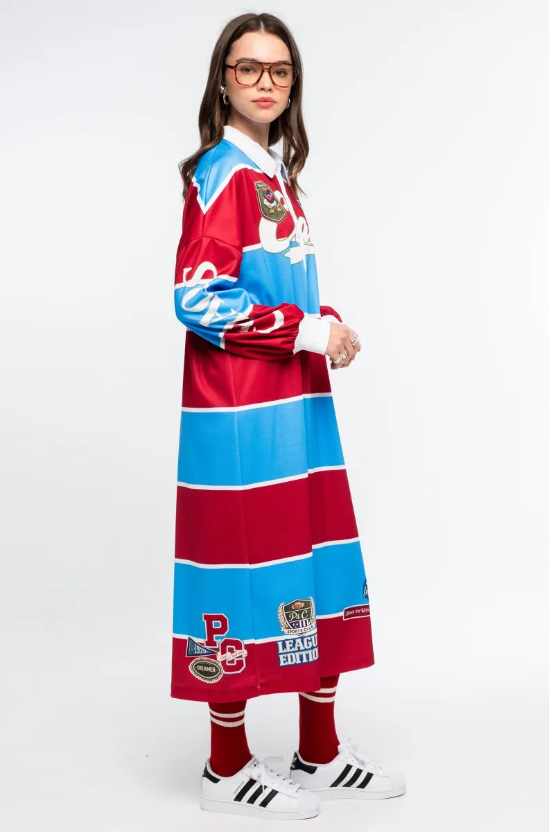 Το Semester Long Dress της Peace + Chaos συνδυάζει τη sporty αισθητική ενός rugby shirt με μια άνετη και μοντέρνα μακριά γραμμή. Κατασκευασμένο από ελαφρύ ύφασμα τύπου φούτερ, διαθέτει ιδιαίτερο placement print με διαδοχικές κόκκινες και μπλε ρίγες, varsity στοιχεία και αθλητικές αναφορές, δημιουργώντας ένα ξεχωριστό statement look.