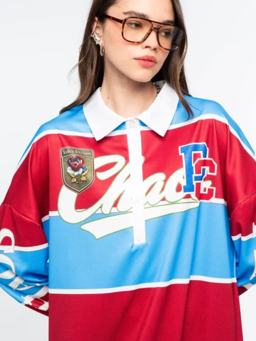Το Semester Long Dress της Peace + Chaos συνδυάζει τη sporty αισθητική ενός rugby shirt με μια άνετη και μοντέρνα μακριά γραμμή. Κατασκευασμένο από ελαφρύ ύφασμα τύπου φούτερ, διαθέτει ιδιαίτερο placement print με διαδοχικές κόκκινες και μπλε ρίγες, varsity στοιχεία και αθλητικές αναφορές, δημιουργώντας ένα ξεχωριστό statement look.