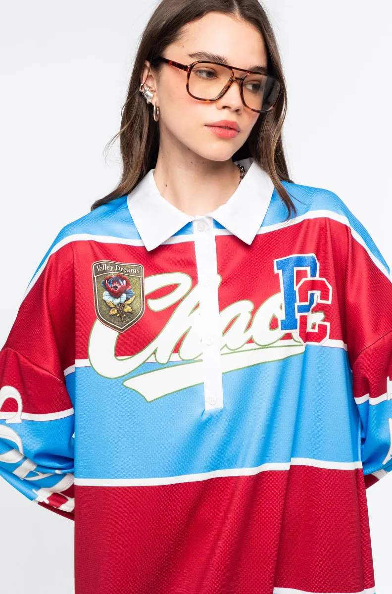 Το Semester Long Dress της Peace + Chaos συνδυάζει τη sporty αισθητική ενός rugby shirt με μια άνετη και μοντέρνα μακριά γραμμή. Κατασκευασμένο από ελαφρύ ύφασμα τύπου φούτερ, διαθέτει ιδιαίτερο placement print με διαδοχικές κόκκινες και μπλε ρίγες, varsity στοιχεία και αθλητικές αναφορές, δημιουργώντας ένα ξεχωριστό statement look.