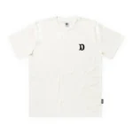 Premium ανδρικό κοντομάνικο T-shirt The Dudes Big D σε off-white χρώμα, με χαρακτηριστικό artwork Big D του καλλιτέχνη McBess.