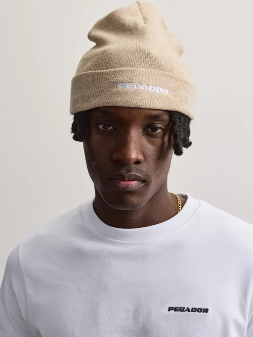 Ο σκούφος Kingdom Logo Beanie της PEGADOR σε μπεζ χρώμα συνδυάζει τη minimal αισθητική με το σύγχρονο streetwear στιλ.
