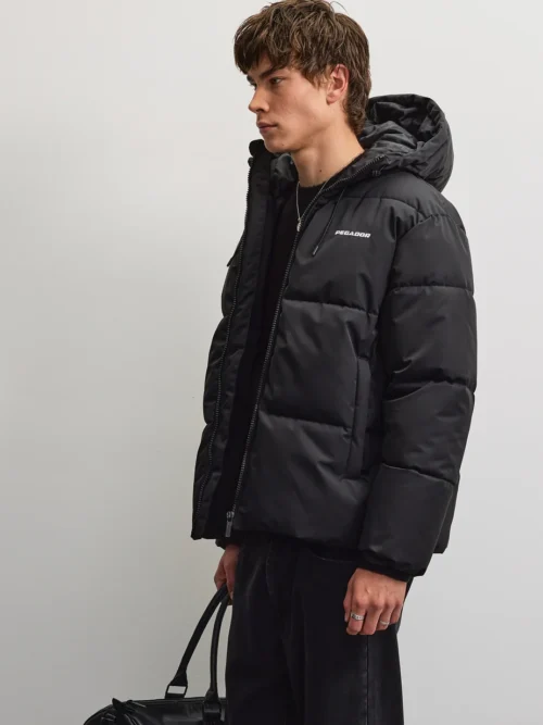 Το Pegador Bertinoro Hooded Puffer Jacket συνδυάζει μοντέρνα streetwear αισθητική με πρακτικό σχεδιασμό για τις κρύες ημέρες. Η oversized γραμμή προσφέρει άνετη εφαρμογή, ενώ οι χαμηλωμένοι ώμοι δημιουργούν relaxed look.