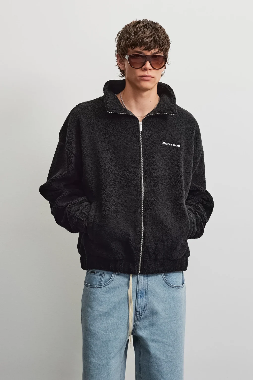 Το Alto Teddy Jacket της PEGADOR σε μαύρο χρώμα συνδυάζει τη μοντέρνα streetwear αισθητική με την άνεση και τη ζεστασιά.