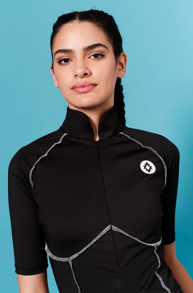 Το Stillness Top της Peace + Chaos συνδυάζει sporty αισθητική, άνεση και ξεχωριστές σχεδιαστικές λεπτομέρειες. Σε μαύρο χρώμα, διαθέτει ραφές σε contrasting απόχρωση που αναδεικνύουν τις καμπύλες και το περίγραμμα του σώματος, ενώ το χαρακτηριστικό Chaka logo σε βινύλιο λειτουργεί ως ιδιαίτερη σχεδιαστική πινελιά.